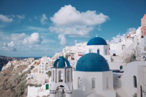 Witte huisjes met blauwe koepeldaken op de kliffen van Santorini bij zonsondergang, met uitzicht op de Egeïsche Zee