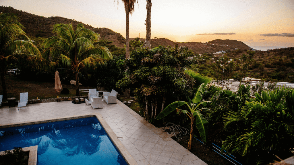 Zwembad met ligbedden en parasols bij een luxe adults only resort aan zee onder bij zonsondergang.