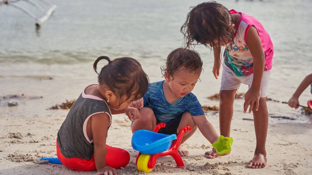 Kinderen spelen op het strand met schepjes en speelgoed tijdens zonvakantie