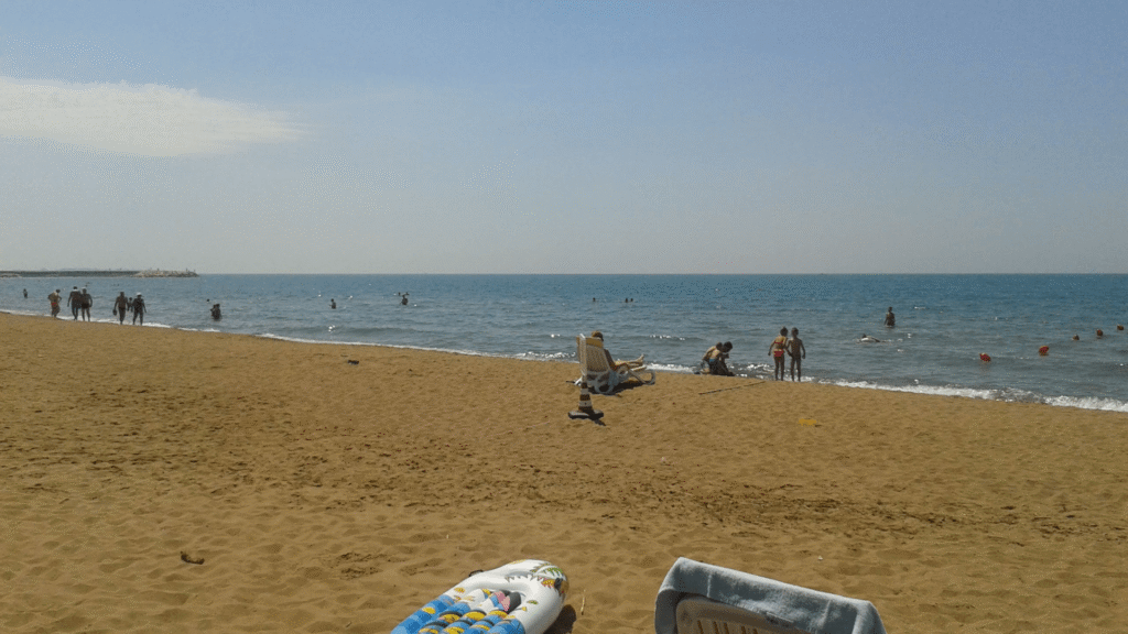 Opblaasbaar SUP-board met stoel en handdoek op het zand bij een rustig strand