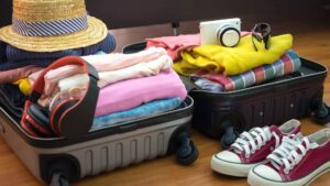 Open koffer met kleurrijke kinderkleding, zonnebrillen, zwembandjes en slippers voor een zonvakantie.