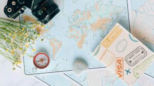 Wereldkaart met bloemen, kompas en reisaccessoires — voorbereiding op het opstellen van een reisbudget.