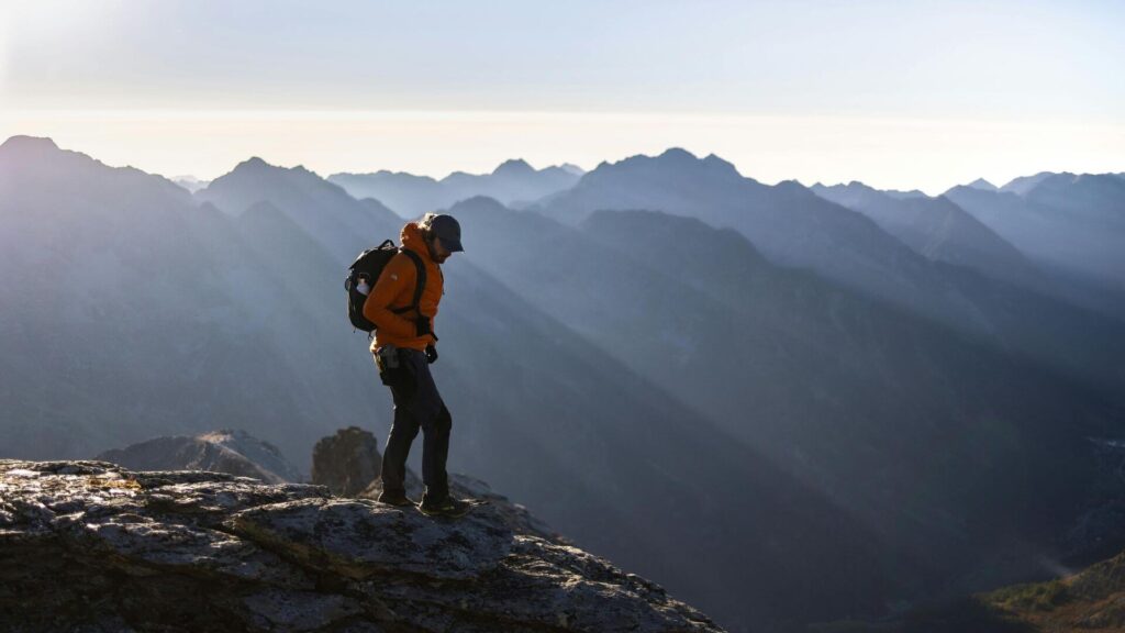 Solo reiziger kijkt uit over een bergtop en zee, genietend van vrijheid en avontuur