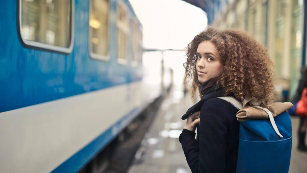 Solo reiziger staat op het treinstation met rugzak klaar voor avontuur