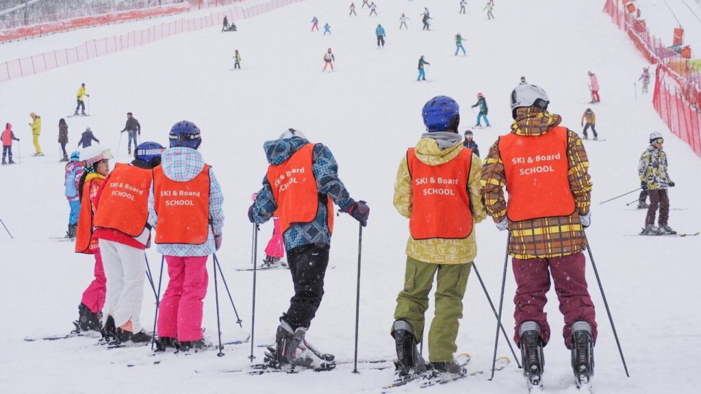 kinderen leren skiën en staan te wachten op een rij