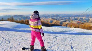 Skigebieden voor beginners 2025/2026: snowboarder kijkt uit over besneeuwde bergen en skilift