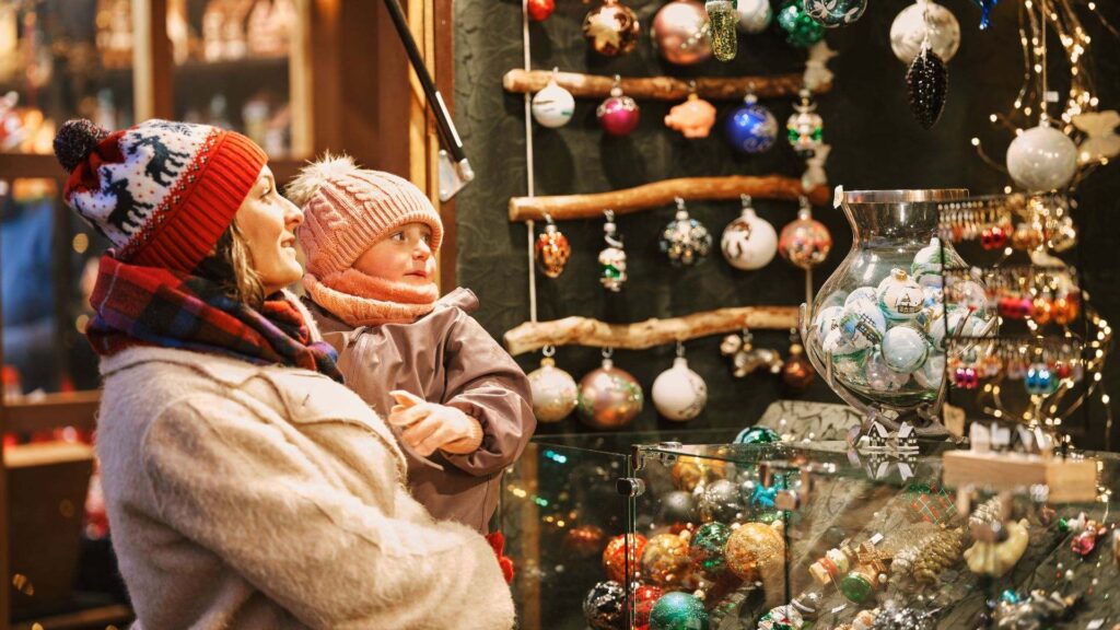 Moeder en kind bewonderen kerstballen en versiering op de kerstmarkt in Maastricht
