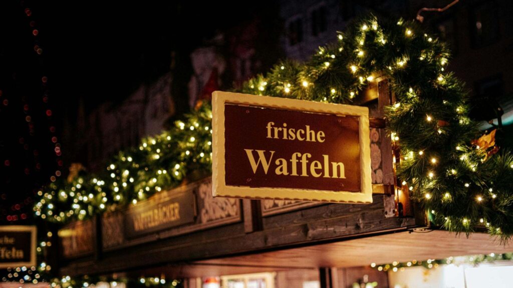 Winterse kerstmarkt in Europa met kraampjes, feestelijke verlichting en bezoekers die rondlopen.