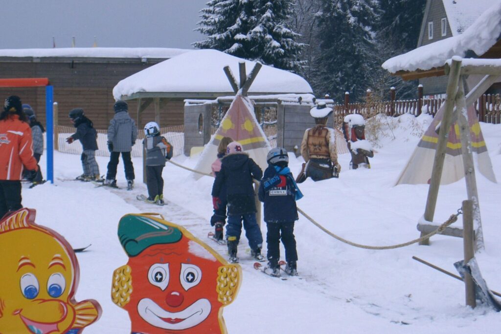 Kinderen volgen skiles op een beginnerspiste tijdens hun eerste wintersport