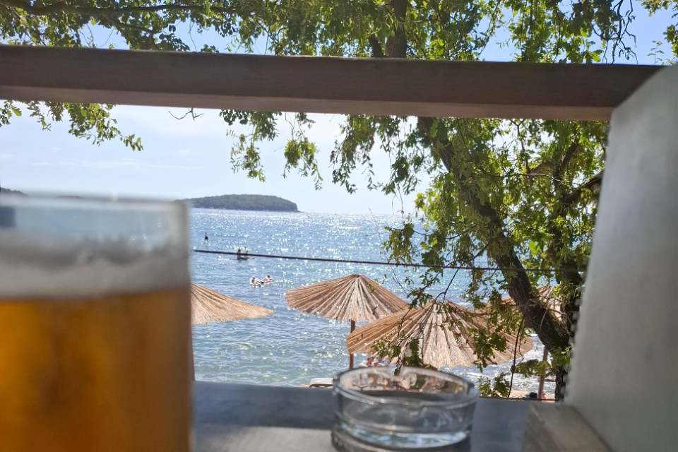 Solo reiziger geniet van drankje op terras aan zee