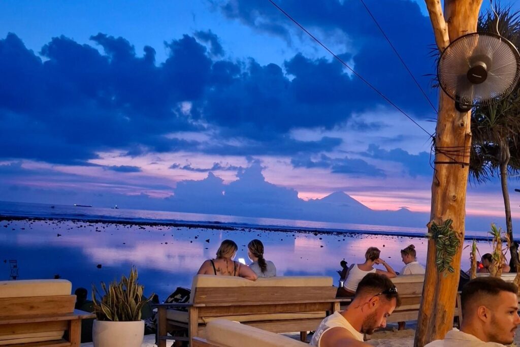 Tropisch strand in Azië tijdens zonsondergang met uitzicht op de zee en palmbomen.