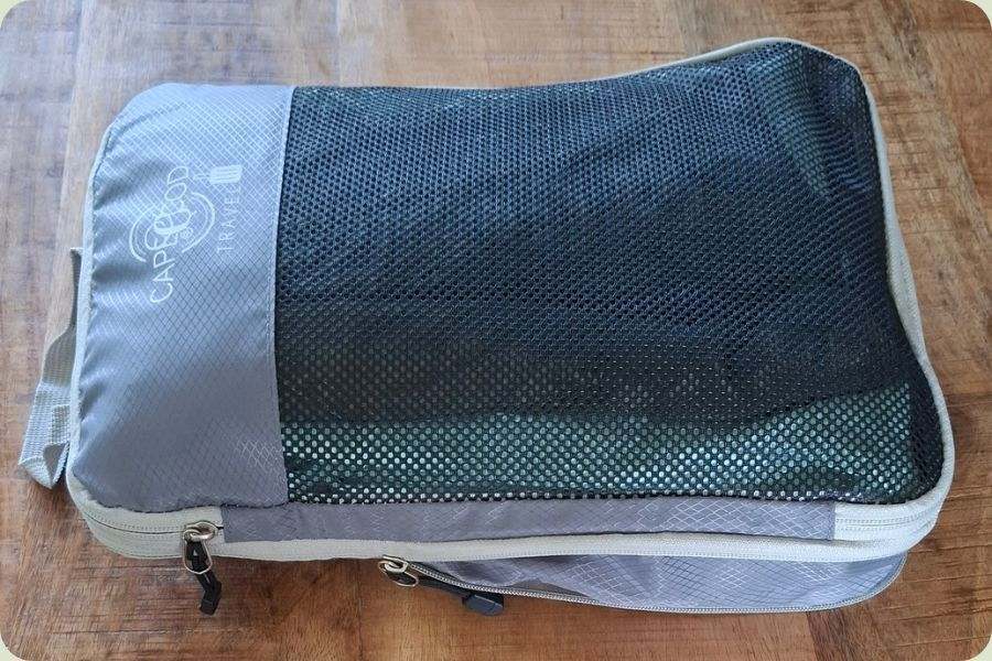 Ingepakte packing cube volledig dichtgeritst en compact gemaakt voor in de koffer.