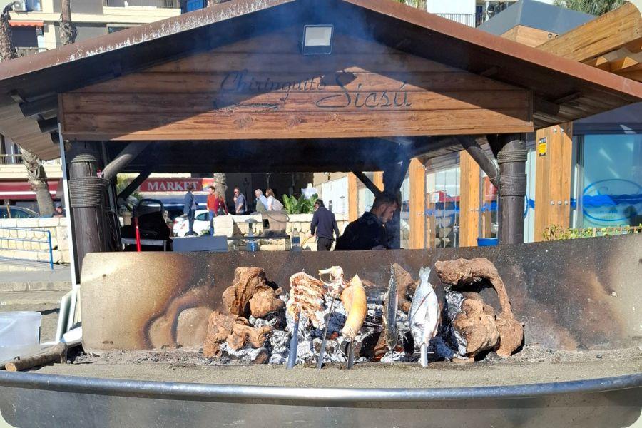 Traditionele espetos de sardinas die worden geroosterd boven een houtvuur in een boot op het strand van Málaga.