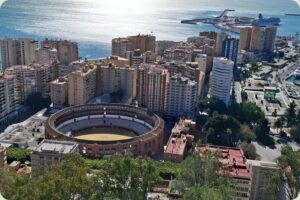 Panoramisch uitzicht over Málaga vanaf Gibralfaro met de ronde stierenvechtersarena Plaza de Toros de La Malagueta en de haven in de verte.