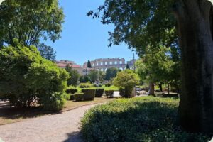 Een doorkijkje vanuit een groen park naar de historische Romeinse Arena in Pula